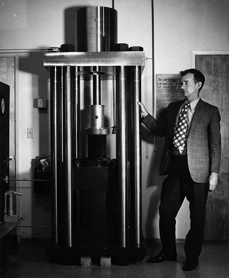 James Byerlee standing next to the triaxial machine